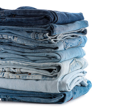 Sustainable fashion and clothing retail, stack of folded blue denim jeans in various shades of wash isolated on a clean white background