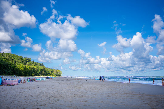 Summer beach with colorful windbreaks and walking people