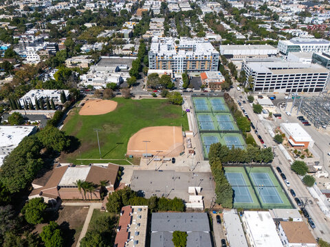 Aerial view of Poinsettia Recreation Center featuring baseball diamonds and tennis courts surrounded by urban residential buildings and lush trees in Los Angeles, California, United States.