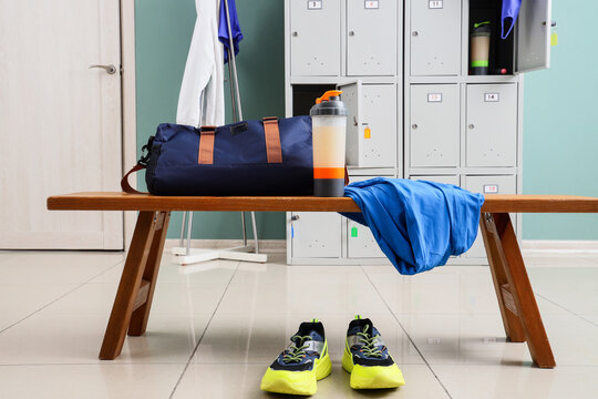 Fitness routine and healthy lifestyle, gym bag with protein shaker and sneakers on a wooden bench in a locker room for workout preparation