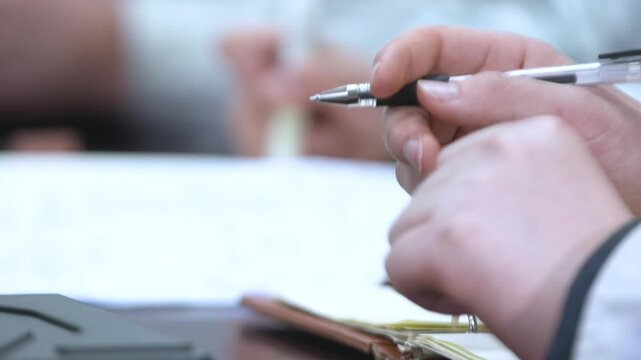 Student Hands Writing Exam Paper in Classroom