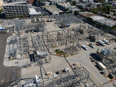 Aerial view of an electrical substation with transformers, metal structures, and utility equipment in an urban industrial area in Los Angeles, California, United States.