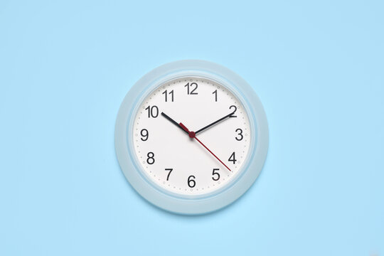 Time management and deadline pressure, wall clock showing ten past ten on a light blue background for business planning and schedule organization