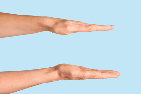 Comparison and measurement concept, two hands held parallel to show size or scale, empty palms facing each other on a light blue background