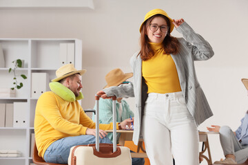 Travel planning and vacation preparation, young woman with suitcase and colleagues in office with summer holiday theme and travel accessories © Pixel-Shot