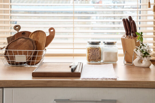 Home cooking and healthy lifestyle, wooden cutting board with kitchen knife and pantry staples on a sunlit countertop in a cozy modern kitchen interior