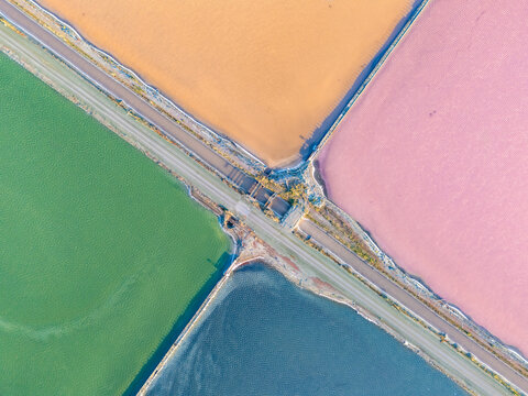 Aerial view of the colorful salt ponds at Bedwell Bayfront Park with geometric levees and vibrant water hues in Menlo Park, California, United States.
