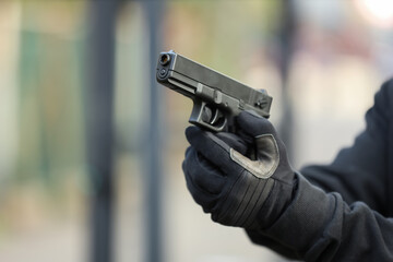 Obraz premium Gun violence and crime prevention person in tactical gloves holding a semi-automatic pistol for security self-defense or law enforcement training