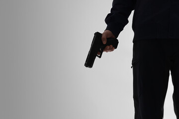 Obraz premium Crime and violence prevention, person holding a handgun in a dark silhouette for security threat, law enforcement or criminal activity