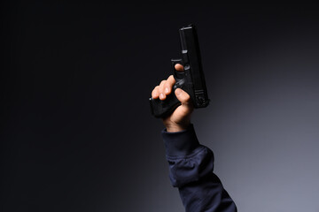 Obraz premium Gun violence and crime prevention, hand holding a black semi-automatic pistol against a dark background for law enforcement and security concepts