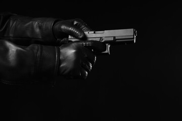 Obraz premium Crime and criminal activity, person in leather gloves holding a handgun in a dark environment for security threat and law enforcement investigation
