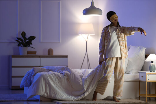 Sleepwalking and insomnia, woman in pajamas with sleep mask wandering in bedroom at night experiencing sleep disorder and parasomnia health issues