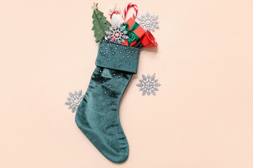 Obraz premium Christmas sock with bell, gift and decorations on beige background. Top view