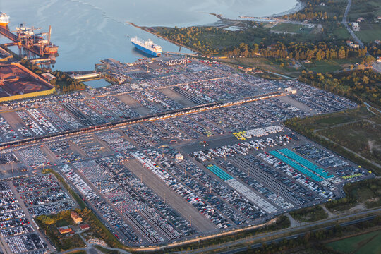 Aerial view of the Sermin car terminal at the Port of Koper with rows of parked vehicles, shipping vessels, and industrial infrastructure in Koper, Koper, Slovenia.