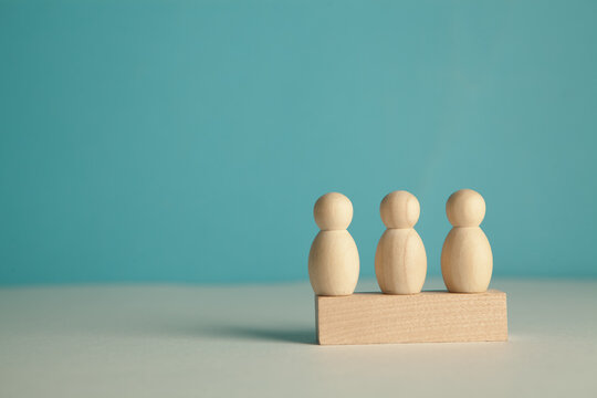 Wooden figures of people stand on a blue background.