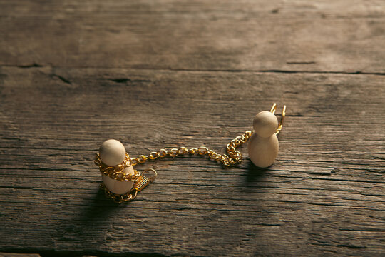 Wooden mannequin with golden chain on table against dark background