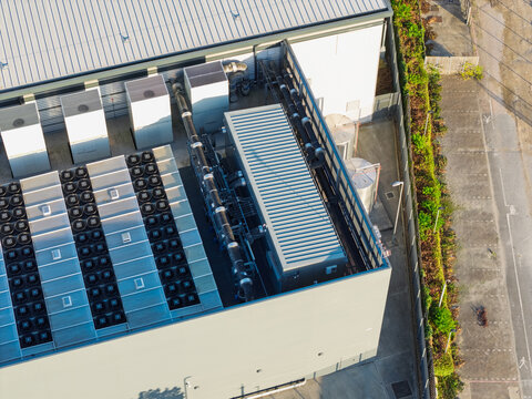 Aerial view of a data center rooftop featuring rows of cooling fans, industrial HVAC units, and metal piping in the United Kingdom.