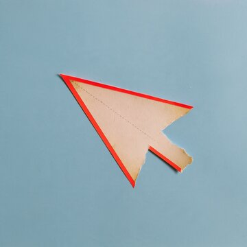 Cursor arrow sticker made of textured aged paper with a red border on a blue background, for interface education and digital navigation