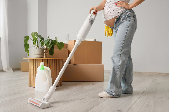 Nesting instinct and home preparation, pregnant woman cleaning house with vacuum cleaner before baby arrival during moving day in new apartment