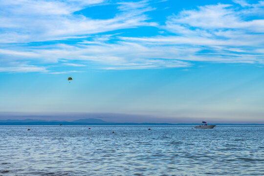 Scenic view of the Adriatic Sea in Bibione, Italy, with a motorboat and parasailing in the sky