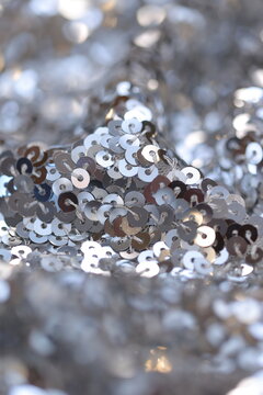 Sparkling silver metallic sequin fabric texture background. Glitzy shiny material for fashion, Christmas, New Year party, and festive holiday decor.