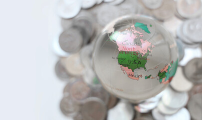 glass globe map ball sphere with a globe on top of it with a stack of silver coins money underneath North America USA US Canada Mexico Grenlandia island Venezuela between Arctic and Atlantic oceans © Maxim Chuev