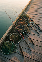 Fototapeta premium Recreational fishing and outdoor leisure, fishing rods and landing nets resting on a wooden pier at sunrise for hobby and sport activity preparation
