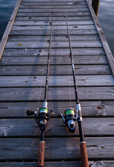 Fototapeta premium Leisure and recreation, two fishing rods with reels resting on a wooden pier at sunrise for outdoor hobby and travel lifestyle photography