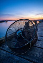 Fototapeta premium Sustainable fishing and coastal economy, crab trap on a wooden pier at sunset with calm water and horizon view for maritime industry and travel themes