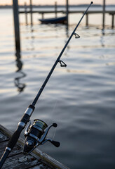 Fototapeta premium Leisure and recreation, fishing rod with spinning reel on a wooden pier at sunset for outdoor hobby and travel lifestyle photography at the lake
