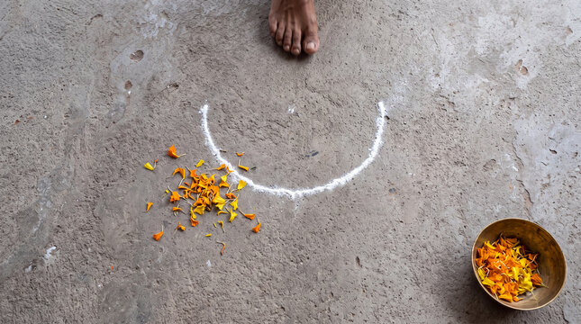 Unfinished Diwali rangoli, first rice-flour arc and loose marigold petals