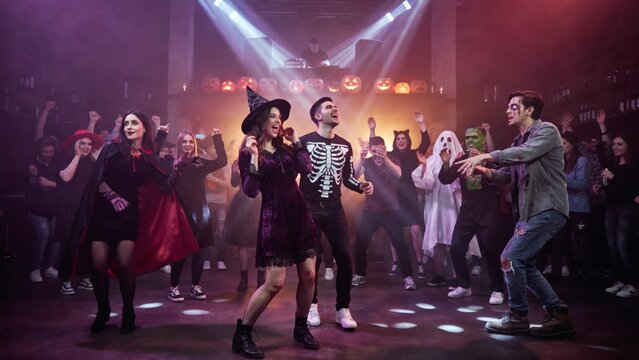 Halloween party celebration with costumed friends dancing in a club