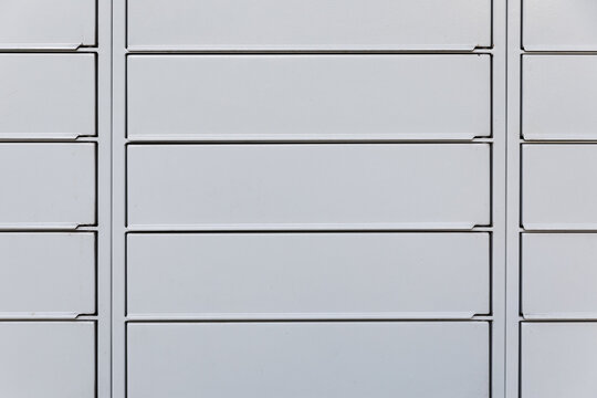 Modern automated parcel locker doors close-up, electronic delivery terminal compartments facade, secure postal storage system exterior, daytime, Warsaw, Poland.