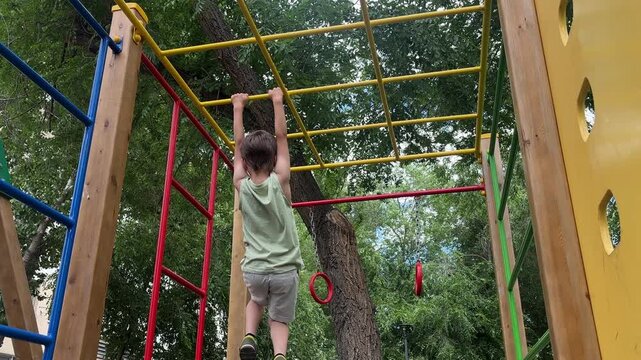 Young child climbing and playing on monkey bars at an outdoor playground. Active childhood, outdoor recreation, exercise and physical activity