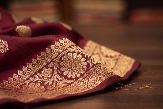 Close-up of gold zari border on a maroon Banarasi silk saree with woven motifs