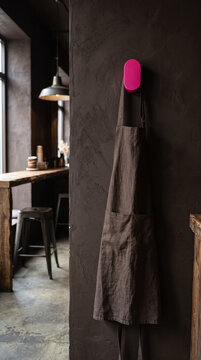 Linen barista apron mockup hanging on pink acrylic wall hook in modern cafe