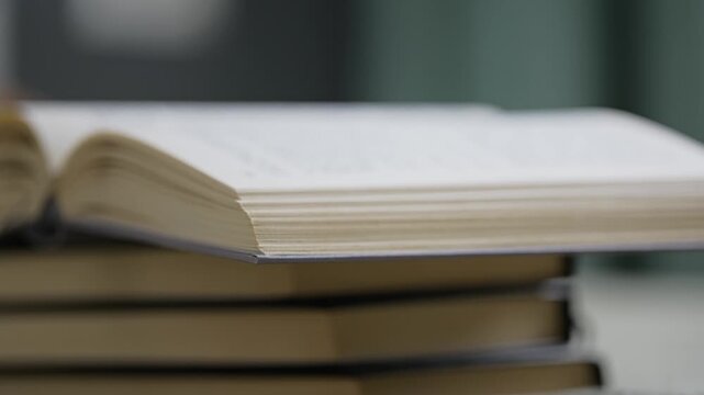 Open book pages on a stack of books in a library, representing knowledge and education