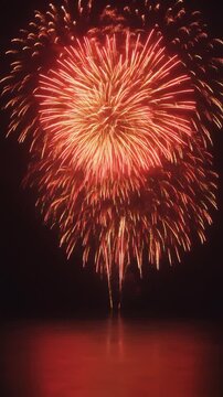 Beautiful red fireworks exploding over the ocean at night, vertical 9:16