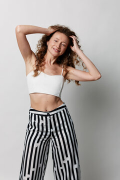 Authentic beauty of a middle-aged woman with natural skin and curly hair posing against a grey background. Concept of body positivity, wellness, and self-care.
