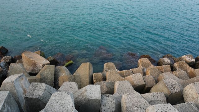 Massive Concrete Tetrapod Breakwater Armor Units Protecting Coastal Shoreline Against Turquoise Sea Waves, Coastal Engineering Infrastructure for Harbor Protection and Erosion Prevention