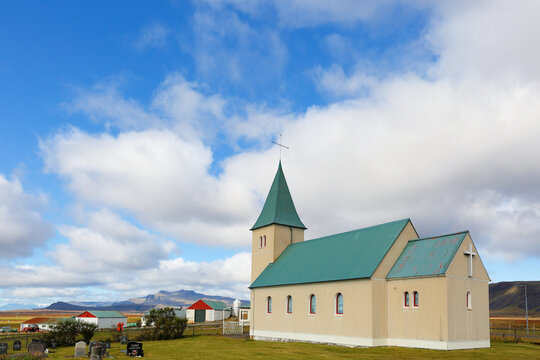Early morning light illuminating Hellnakirkja, a historic white church with a green roof, perched along the rugged coastline of Hellnar on the Sn&aelig;fellsnes Peninsula in West Iceland.