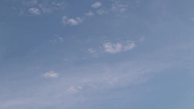 Sky with thin light white clouds in the daytime, natural background, space, height. Clear blue sky with thin, scattered white clouds. Minimalist landscape. View from below on a natural blue sky