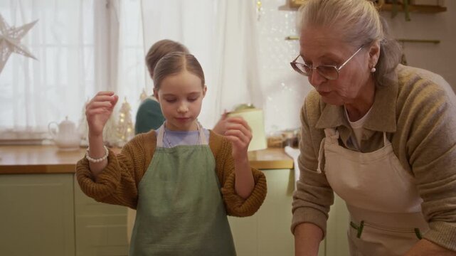 Caucasian senior woman kneading dough with children helping in kitchen. Clip suited for family cooking workshops, multigenerational lifestyle projects, traditional culinary advertising