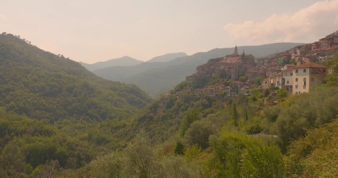 Scenic view of Apricale, a historic medieval hilltop village surrounded by lush green mountains and valleys in Liguria, northern Italy.