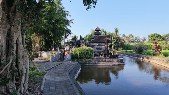 Ancient water temple in Ubud Bali featuring traditional stone architecture amidst lush greenery and tropical trees, peaceful atmosphere for travel, cultural heritage, and spiritual destination