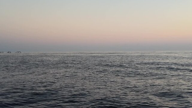 Calm ocean surface at dawn in Lovina, Bali with gentle rippling water texture and soft pastel sunrise sky, perfect for meditation backgrounds, travel themes, tranquil nature atmosphere, serenity