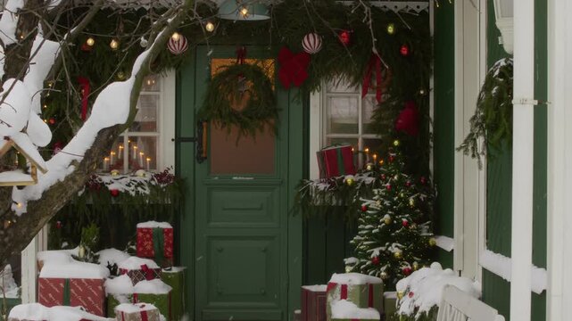 Snow falling on decorated Christmas porch with gift boxes, festive wreath and illuminated garland. Ideal for holiday marketing campaigns, seasonal winter promotions and greeting video backgrounds