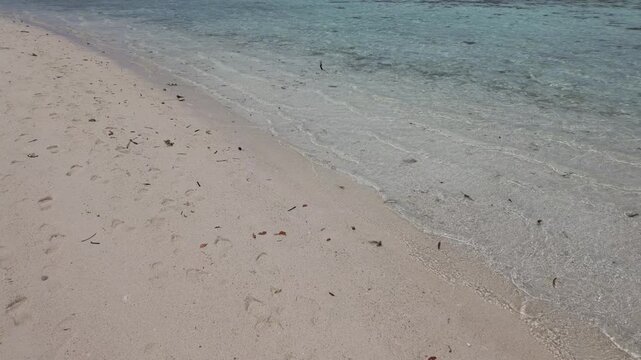 Clear tropical sea water gently washing over white sandy shore of Cemara Kecil island, calming ocean waves, peaceful nature background, travel destination, serene coastline, coastal texture, summer