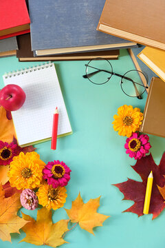 Notebook, pencils, learning books, eyeglass, flowers and autumn maple leaves on table. Teacher's day holiday, education, 1 september, back to school, Day of knowledge concept. top view. copy space