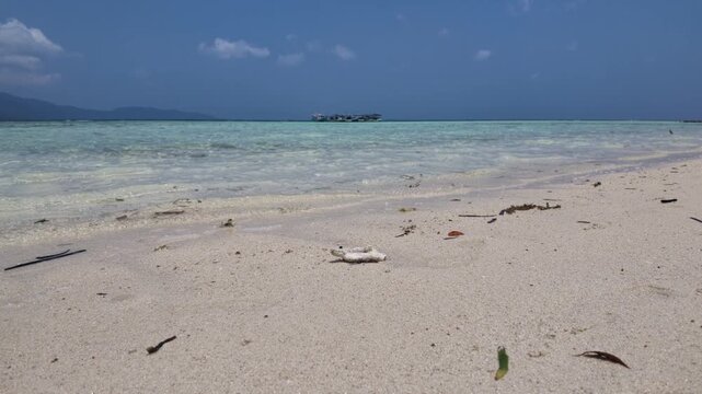 Clear turquoise tropical waters at Cemara Kecil island with sandy shoreline and distant boat, serene coastal seascape for travel inspiration, nature tourism, island exploration, summer holiday vibes